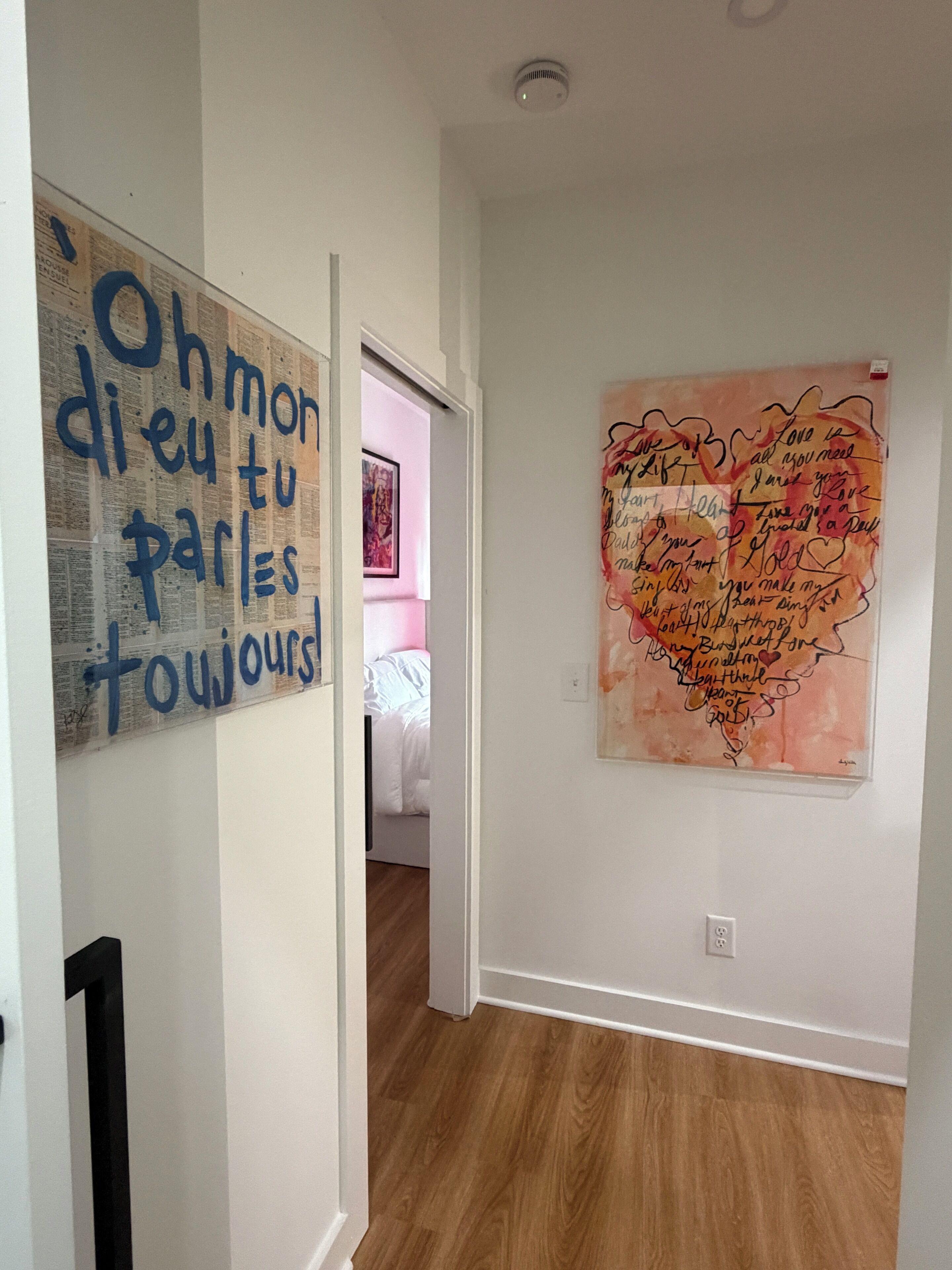 A hallway with a wall-mounted sign and a large heart-shaped artwork.