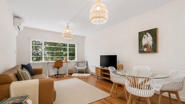 Ein modernes Wohnzimmer mit Sofa, Fernseher, Esstisch mit Stühlen und einem Bild an der Wand.