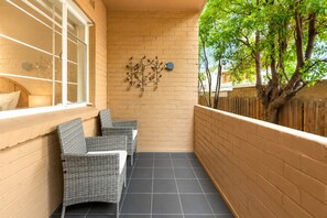 A narrow balcony with two wicker chairs, a brick wall, and a decorative metal wall art piece. - St George's Gate - Toorak by Ready Set Stay (Toorak)