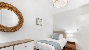 Ein Schlafzimmer mit einem Bett, einem Nachttisch, einer Lampe und einem großen Spiegel.