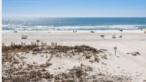 Ein Strand mit Sand, einem Zaun und blauem Himmel.