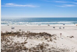 Ein Strand mit Sand, einem Zaun und blauem Himmel.