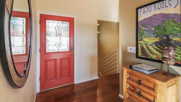 A red door with a glass panel, a wooden staircase, and a wall-mounted poster. - Peachy Canyon Place by Avantstay Vineyard Deck Views Near Wineries (Paso Robles)