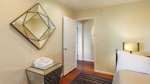 A hotel room with a bed, a bedside lamp, a mirror, a door, and a small table with towels. - Peachy Canyon Place by Avantstay Vineyard Deck Views Near Wineries (Paso Robles)