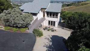 A two-story house with a sloped roof, a front porch, and a driveway leading to a garage. - Peachy Canyon Place by Avantstay Vineyard Deck Views Near Wineries (Paso Robles)