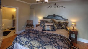 Una camera da letto con un letto grande, due comodini, una sedia e un elemento decorativo a parete.