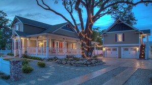 Una casa a due piani con un portico, un garage e un grande albero decorato con luci.