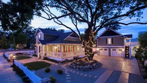 A two-story house with a porch, garage, and a large tree with lights. - Bliss House by Avantstay Victorian Charm + Gazebo Yard + Corn Hole Walk to Dining + Park (Paso Robles)
