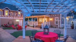 A covered patio area with a table and chairs, a pergola with string lights, and a house with a porch. - Bliss House by Avantstay Victorian Charm + Gazebo Yard + Corn Hole Walk to Dining + Park (Paso Robles)