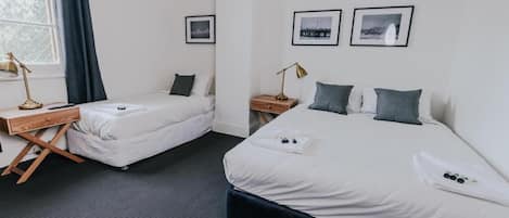 A hotel room with two single beds, a desk, and a window with curtains.