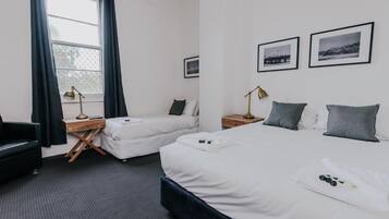 Ein Hotelzimmer mit zwei Einzelbetten, einem Schreibtisch, einem Stuhl und einem fenster mit Vorhängen.