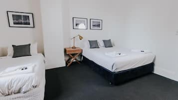 Ein Hotelzimmer mit zwei Betten, einem Nachttisch, einer Lampe und gerahmten Bildern an der Wand.
