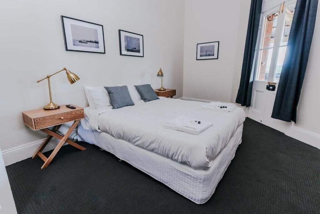 Ein ordentlich eingerichtetes Schlafzimmer mit einem Bett, Nachttischen und gerahmten Bildern an der Wand.