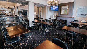 A restaurant with a bar area, multiple tables, and chairs. - Holmesville Hotel (Holmesville)