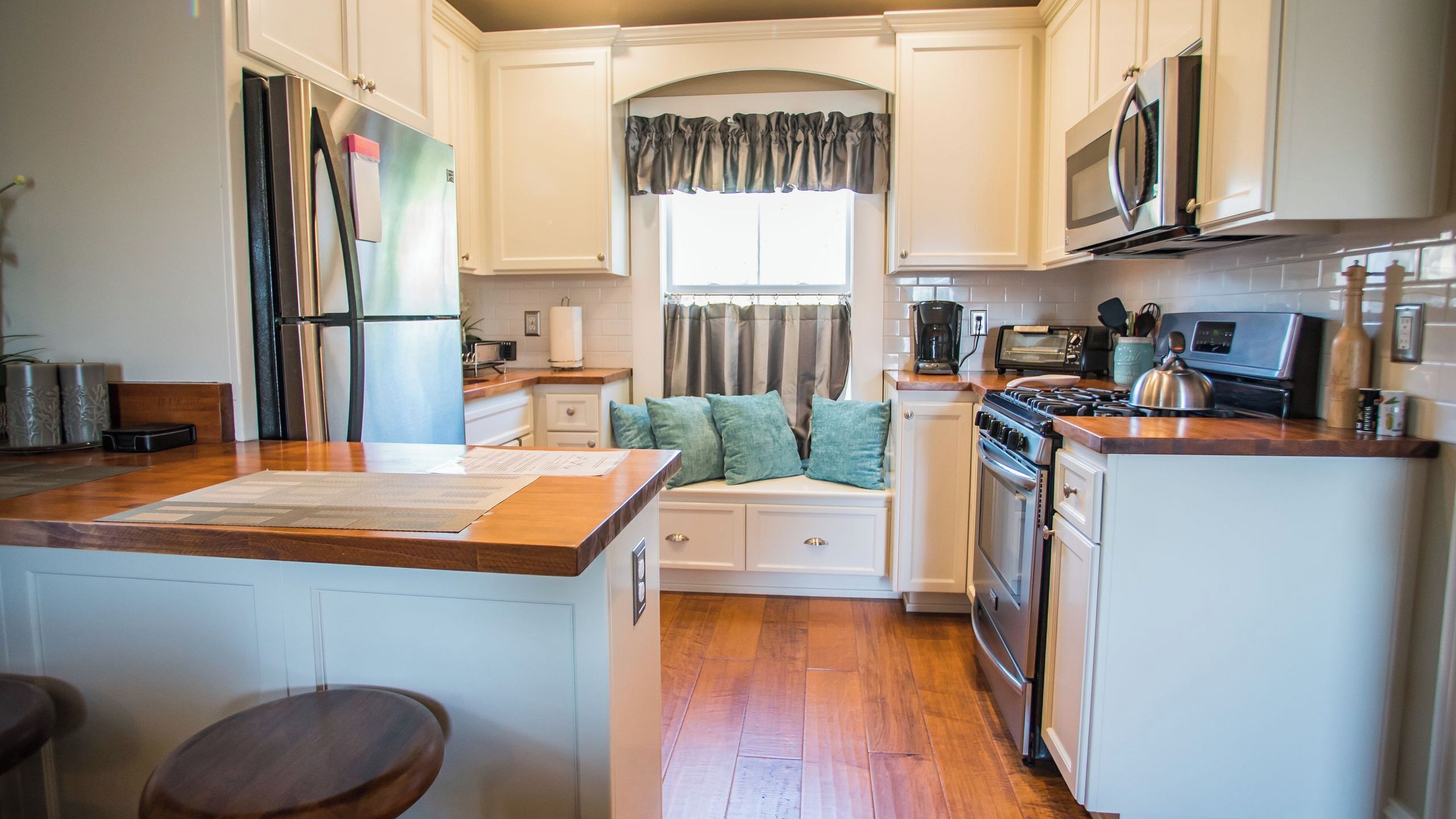 A kitchen with a central island, a stove, microwave, and a refrigerator.