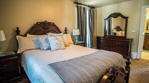 A bedroom with a large bed, a dresser, a mirror, and a nightstand with a lamp. - Baby Bliss by Avantstay Steps to Dining + Shops Paso Robles Wine Country (Paso Robles)