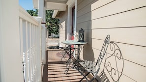 Un patio con tavolo e sedia in metallo, una lanterna e un muro decorativo.