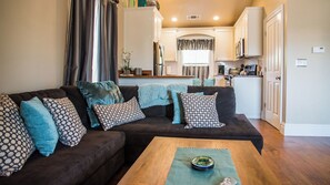 A living room with a dark brown sectional sofa, patterned cushions, and a wooden coffee table. - Baby Bliss by Avantstay Steps to Dining + Shops Paso Robles Wine Country (Paso Robles)