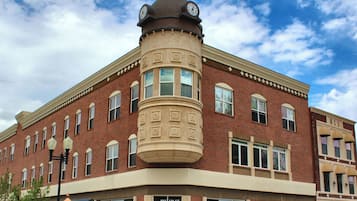 A corner building with a clock tower, multiple windows, and a street lamp.