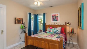 A bedroom with a wooden bed, a ceiling fan, a window with blue curtains, and artwork on the walls. - The Sycamore by Avantstay Fenced Yard + BBQ Walk to Downtown Wineries (Paso Robles)