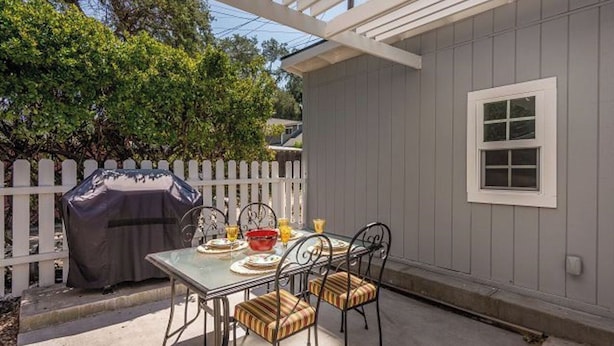 A patio with a table and chairs, a covered grill, and a white fence. - The Sycamore by Avantstay Fenced Yard + BBQ Walk to Downtown Wineries (Paso Robles)
