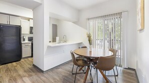 Eine moderne Küche mit weißen Schränken, einem schwarzen Kühlschrank und einem Essbereich mit rundem Tisch und Stühlen.