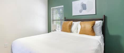 Une chambre d’hôtel avec un lit, une fenêtre avec des stores et une œuvre d’art accrochée au mur.