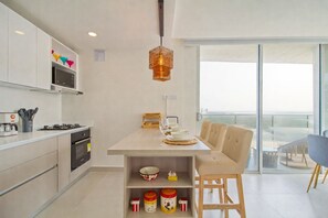 Eine moderne Küche mit Essbereich, ein Balkon mit Aussicht und einer Pendelleuchte.