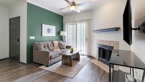 A living room with a sofa, coffee table, and fireplace. - Landing | Chic 2BD, Gym, Courtyard (Allen)