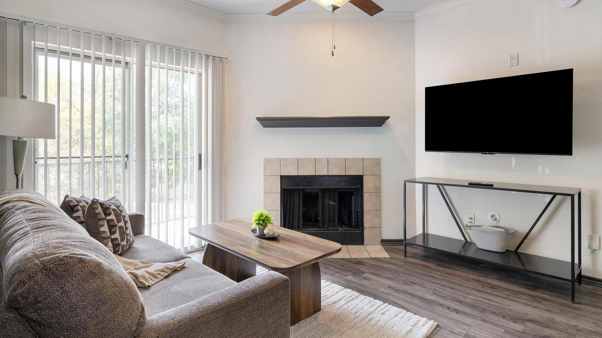 Ein Wohnzimmer mit Sofa, Couchtisch, Kamin, Fernseher und Deckenventilator.