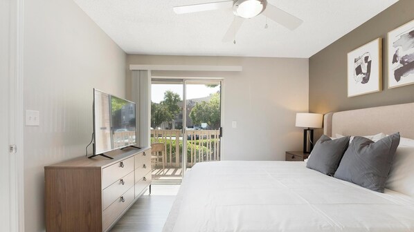 Une chambre avec un lit, une télévision, un ventilateur de plafond, une table de chevet et un balcon avec vue.