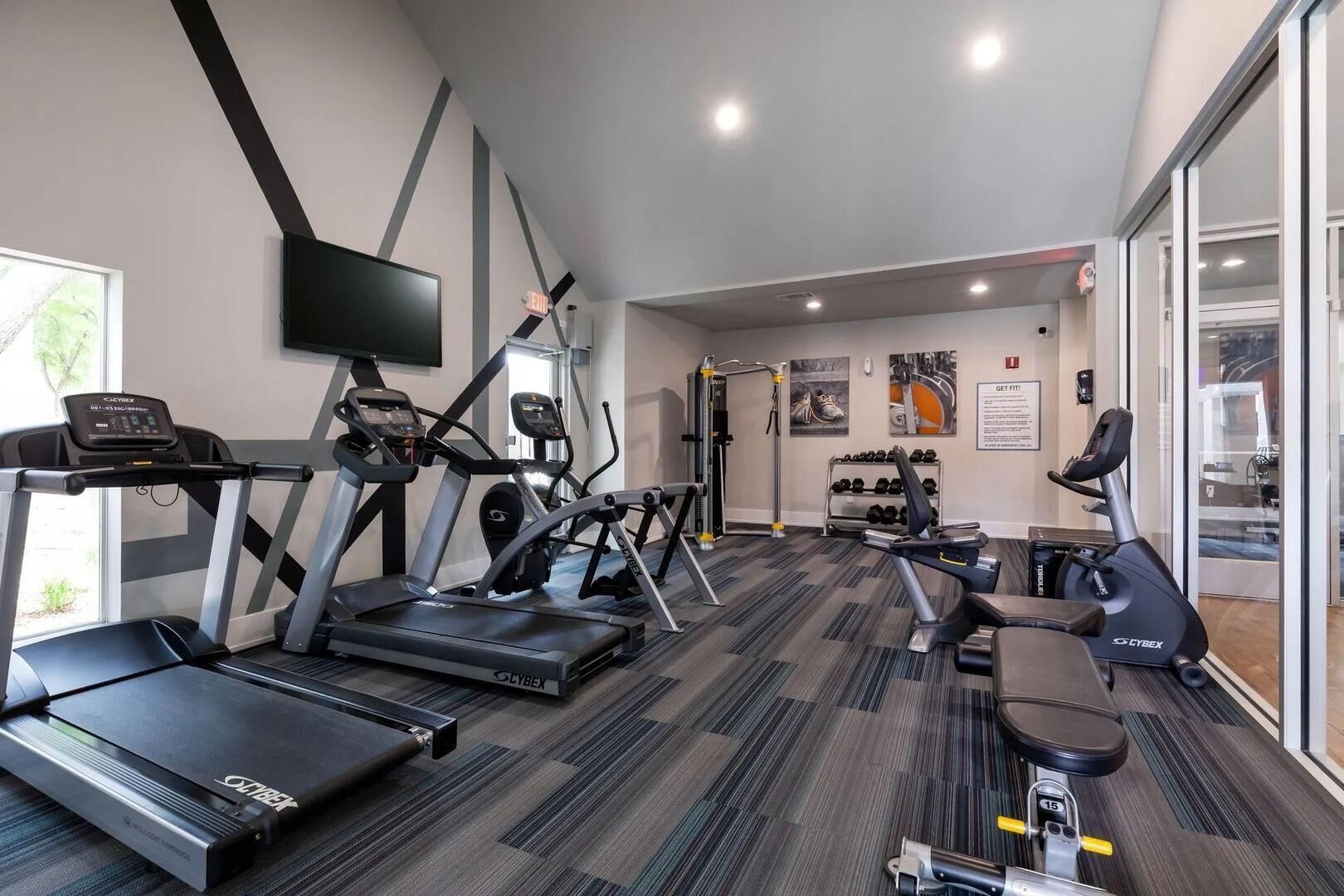 A gym with treadmills, elliptical machines, and a weight bench.
