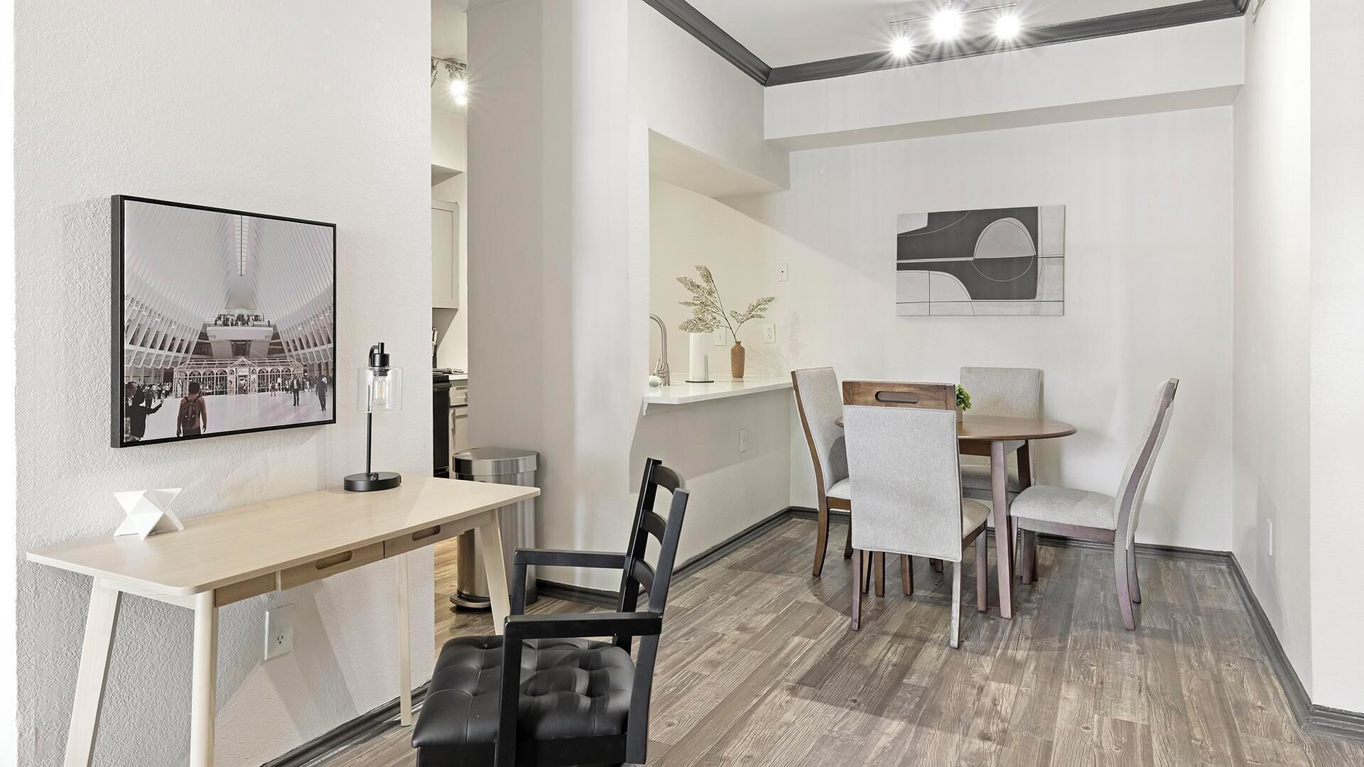 Une chambre d’hôtel moderne avec un coin repas, un grand tableau encadré et une petite table avec des chaises.