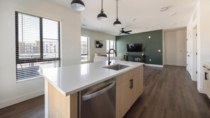 Uma cozinha moderna com ilha central, máquina de lavar louça embutida e ventoinha no teto.