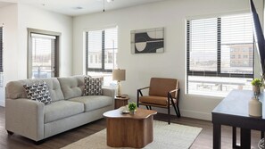 Un salon avec un canapé, un fauteuil, une table basse et un tableau accroché au mur.