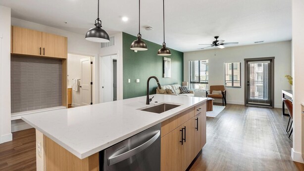 A modern kitchen with a central island, stainless steel dishwasher, and pendant lighting. - Landing | Stylish 1BD, Game Room, Courtyard (Goodyear)