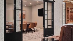 A conference room with a table and chairs, a television, and a sliding door leading to another room. - Landing | Stylish 1BD, Game Room, Courtyard (Goodyear)