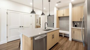 A modern kitchen with a central island, stainless steel appliances, and pendant lighting. - Landing | Beautiful 2BD, Gym, Game Room (Goodyear)