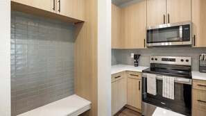 Una cucina moderna con mobili in legno, un forno a microonde in acciaio inossidabile e un forno nero.