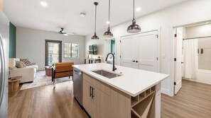 A modern kitchen with a central island, pendant lighting, and a view to the living area. - Landing | Stylish 2BD, Gym, Clubhouse (Goodyear)