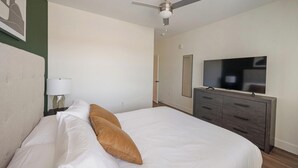 Een hotelkamer met een bed, een televisie, een dressoir en een plafondventilator.