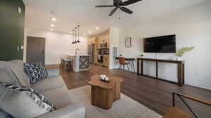 Een moderne woonkamer met een bank, salontafel en een eethoek met stoelen.