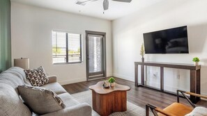 Ein Wohnzimmer mit einer Couch, einem Couchtisch und einem an der Wand montierten Fernseher.