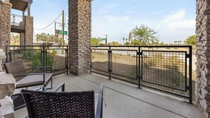 A balcony with stone pillars, a metal fence, and outdoor furniture. - Landing | Stylish 1BD, Clubhouse, Game Room (Goodyear)