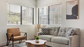 A living room with a sofa, a chair, a lamp, and a painting on the wall. - Landing | Stunning 2BD, Gym, Courtyard (Goodyear)