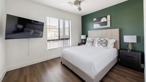 Ein Schlafzimmer mit einem Bett, Nachttischen, einem Fernseher und einem Deckenventilator.