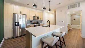 A modern kitchen with a central island, stainless steel appliances, and wooden cabinetry. - Landing | Beautiful 1BD, Clubhouse, Courtyard (Goodyear)