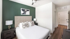 A bedroom with a bed, nightstands, a ceiling fan, and a door. - Landing | Stunning 1BD, Courtyard, Clubhouse (Goodyear)