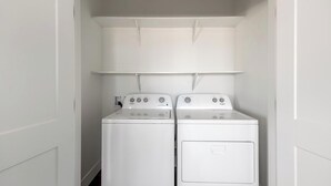 Ein Waschraum mit zwei weißen Whirlpool Waschmaschinen und Trocknern, einer weißen Decke und einer weißen Tür.