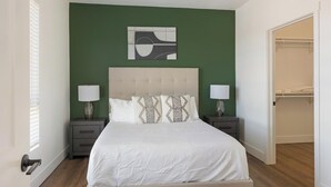 A bedroom with a bed, two nightstands, a headboard, a wall art piece, and a closet. - Landing | Stylish 2BD, Gym, Courtyard (Goodyear)